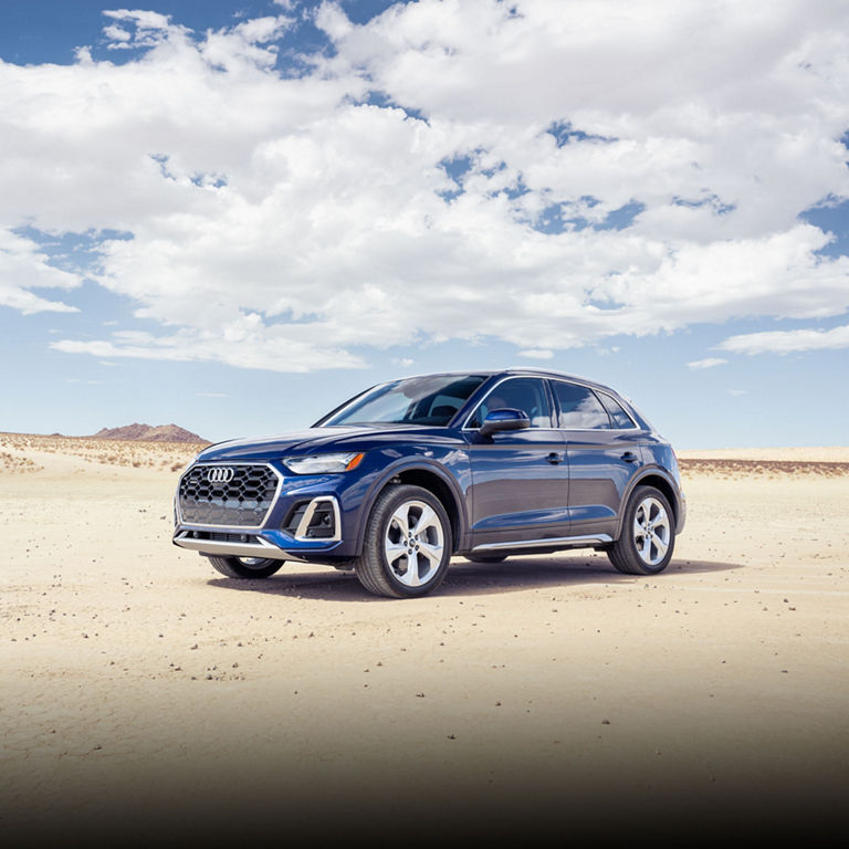 Three-quarter front view fo a blue Audi Q5 parked in a desert. 