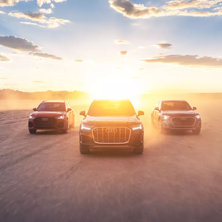 Three Audi SUV models driving alongside each other in the desert. 