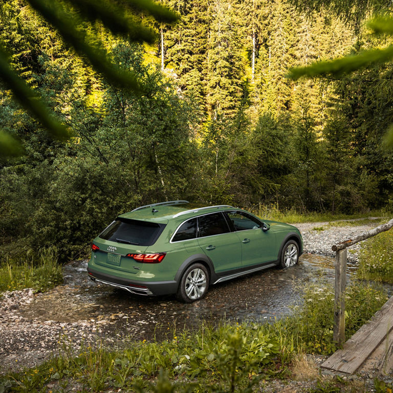 Three-quarter rear view of the Audi A4 allroad® driving on a dirt road.