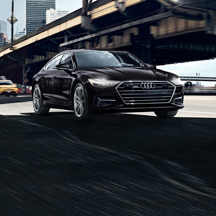 Three-quarter front view of the Audi A7 TFSI® e accelerating. 