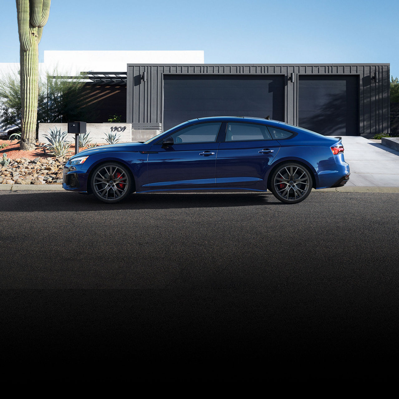 Side view of the Audi A5 Sportback parked in front of a modern home.