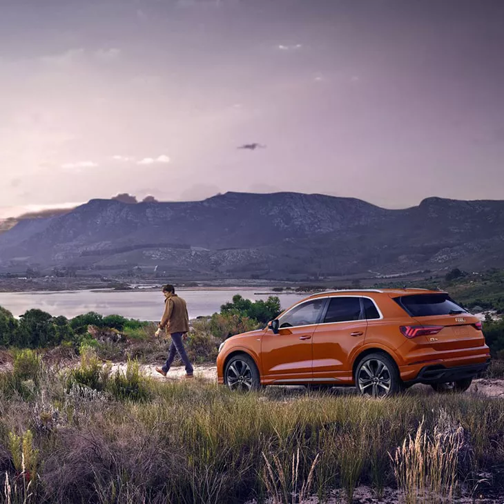Side profile of the Audi Q3 parked with a scenic background.
