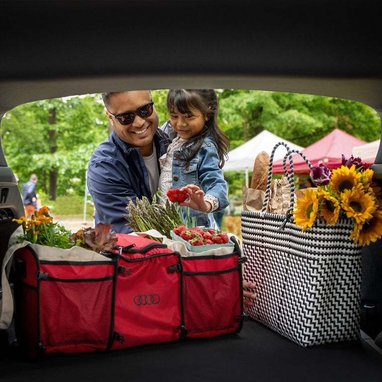 Father and daughter putting a bag into the backseat of an Audi Q4 e-tron.