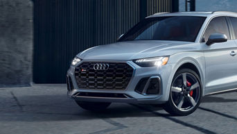 A silver Audi SQ5 parked in front of a garage. 