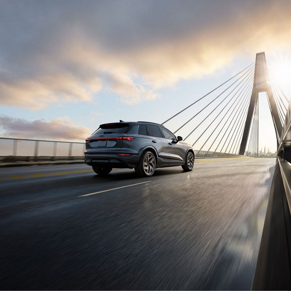 Three-quarter rear view of the Audi SQ6 e-tron accelerating on city bridge.