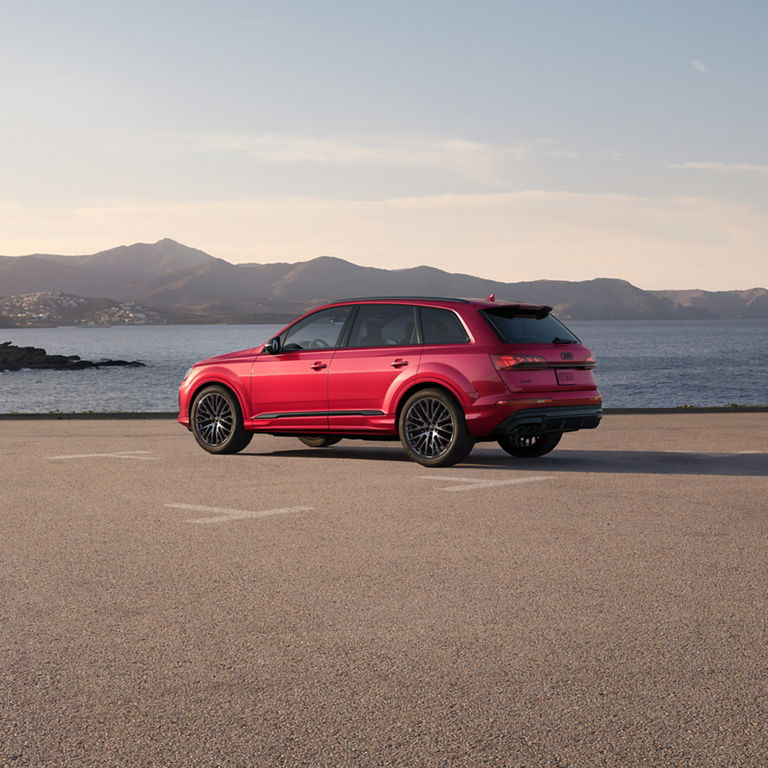 Three-quarter side view of a red Audi SQ7 parked by a waterfront.