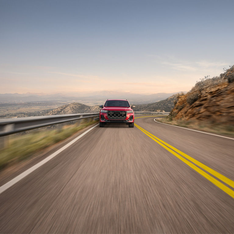 Front profile of a red Audi SQ7 accelerating. 