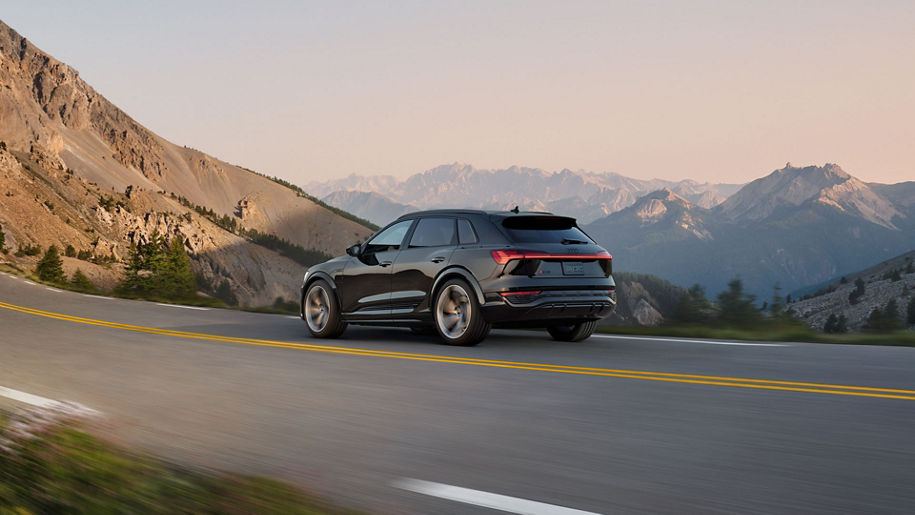 Side-view of the Audi SQ8 e-tron accelerating on a mountain road.