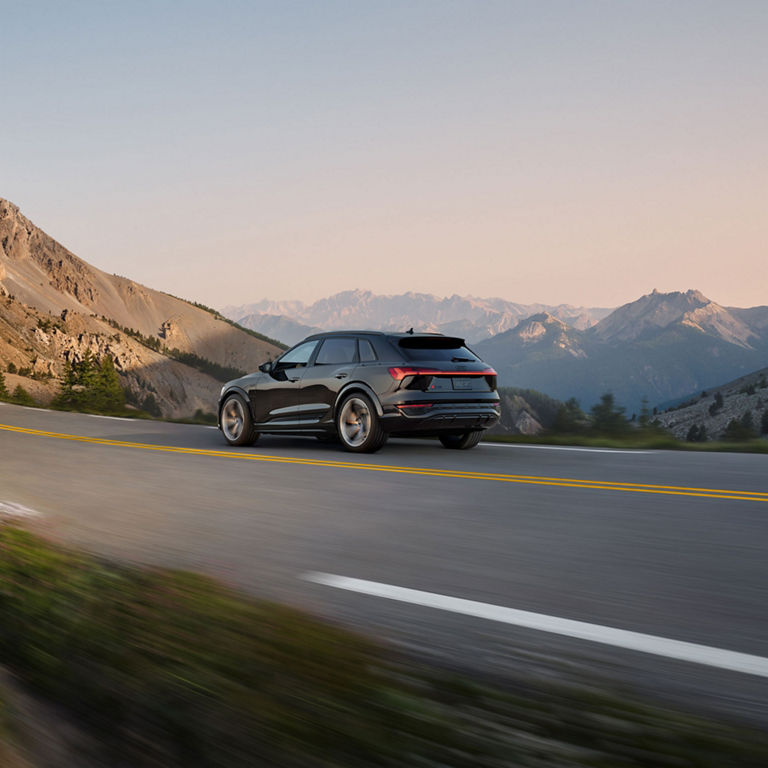 Side-view of the Audi SQ8 e-tron accelerating on a mountain road.