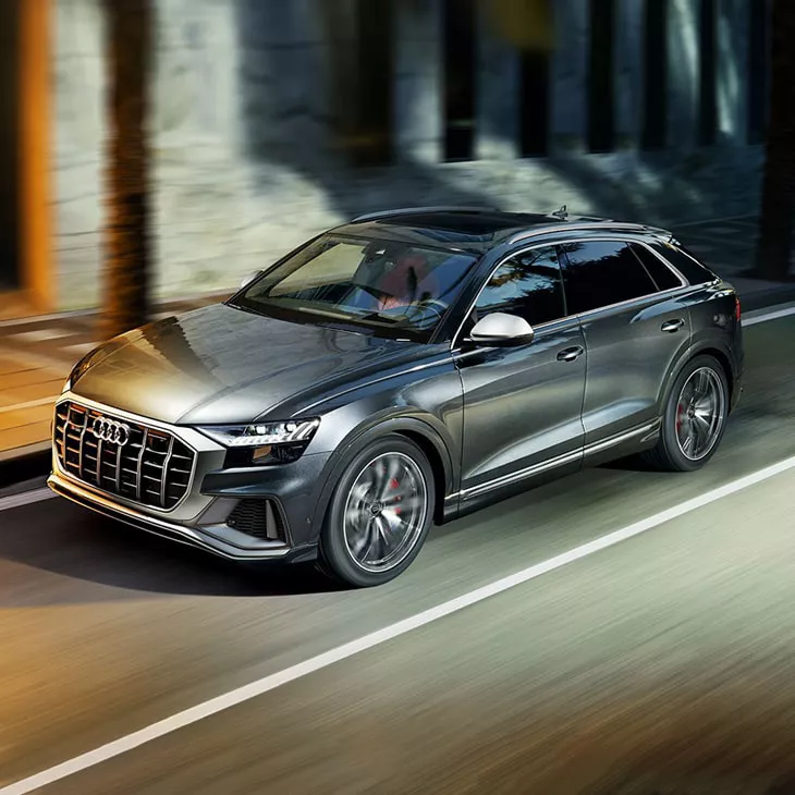 Three-quarter front profile of the Audi SQ8 driving on the road.