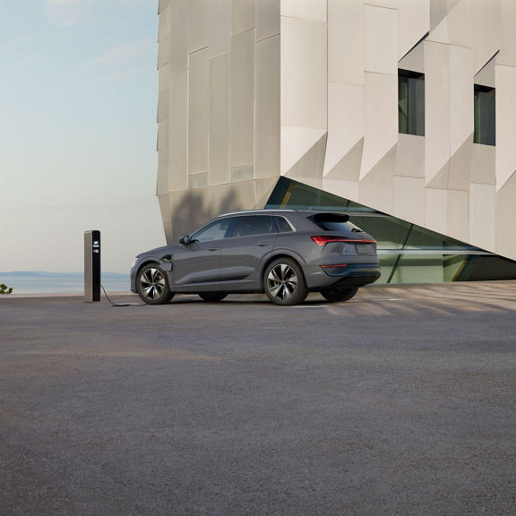 Side profile of a gray Audi Q8 e-tron parked and charging.