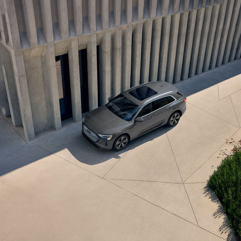 Aerial view of a gray Audi Q8 e-tron parked next to a building.