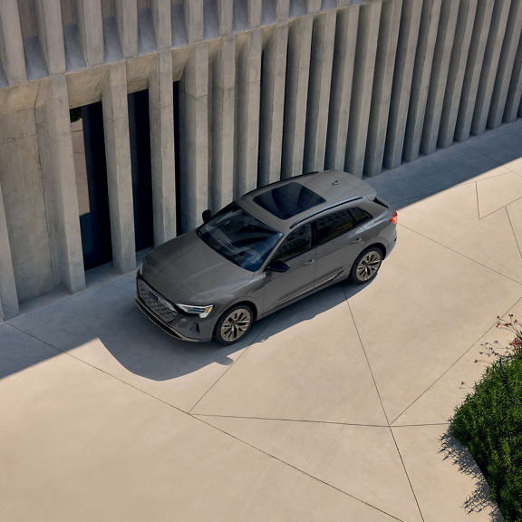 Aerial view of a gray Audi Q8 e-tron parked next to a building.