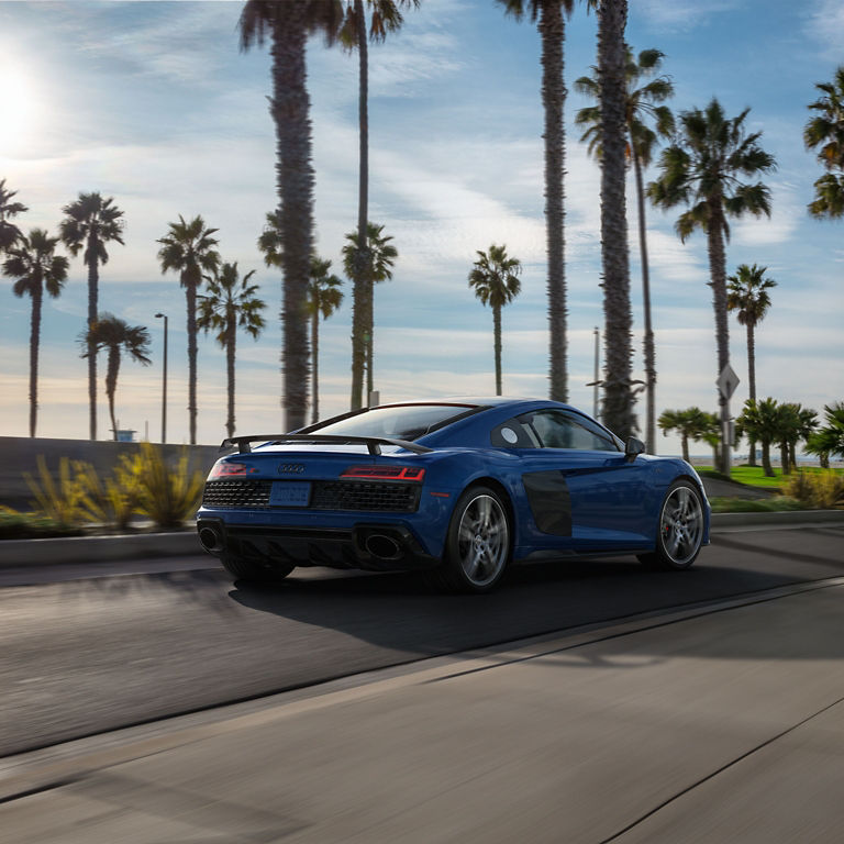 Three-quarter rear profile of the Audi R8 Coupe accelerating.