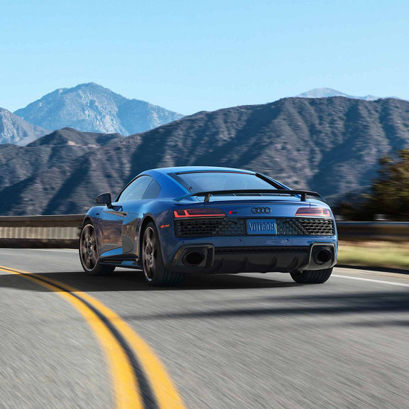 Rear view of the Audi R8 Coupe driving along a winding mountain road. 