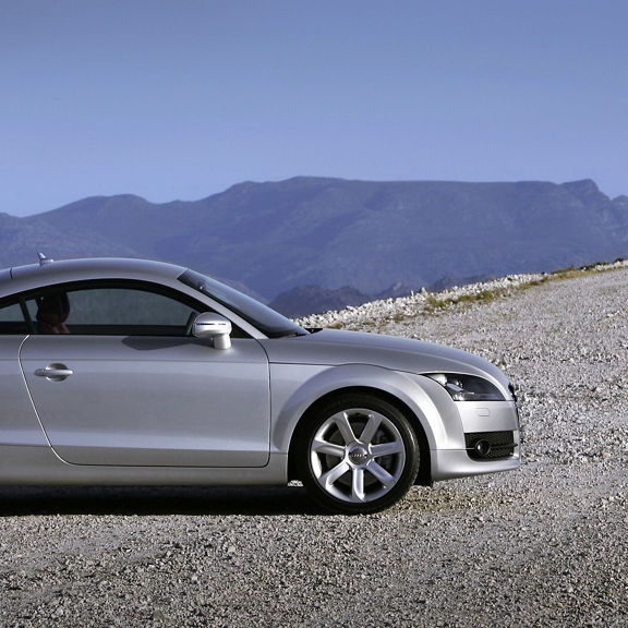 A silver Audi TT Coupe parked looking over a mountainous field.