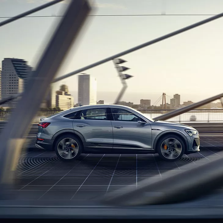 Side profile of the Audi e-tron® Sportback driving on the road.