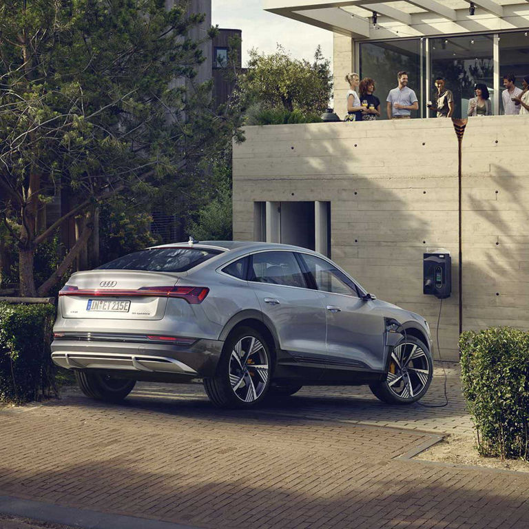 Audi e-tron® Sportback charging in front of a house. 