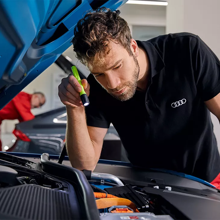 An Audi technician inspecting a vehicle.