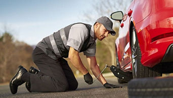 An Audi mechanic working on a car on the side of the road. 