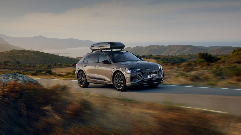 A bike strapped on to a bike rack on top of a blue Audi e-tron. 
