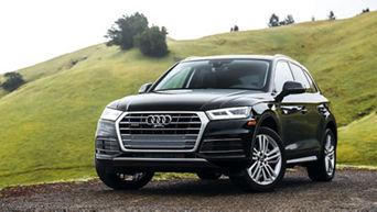 Photo of an Audi Q5 parked near a green hill on a spring day.