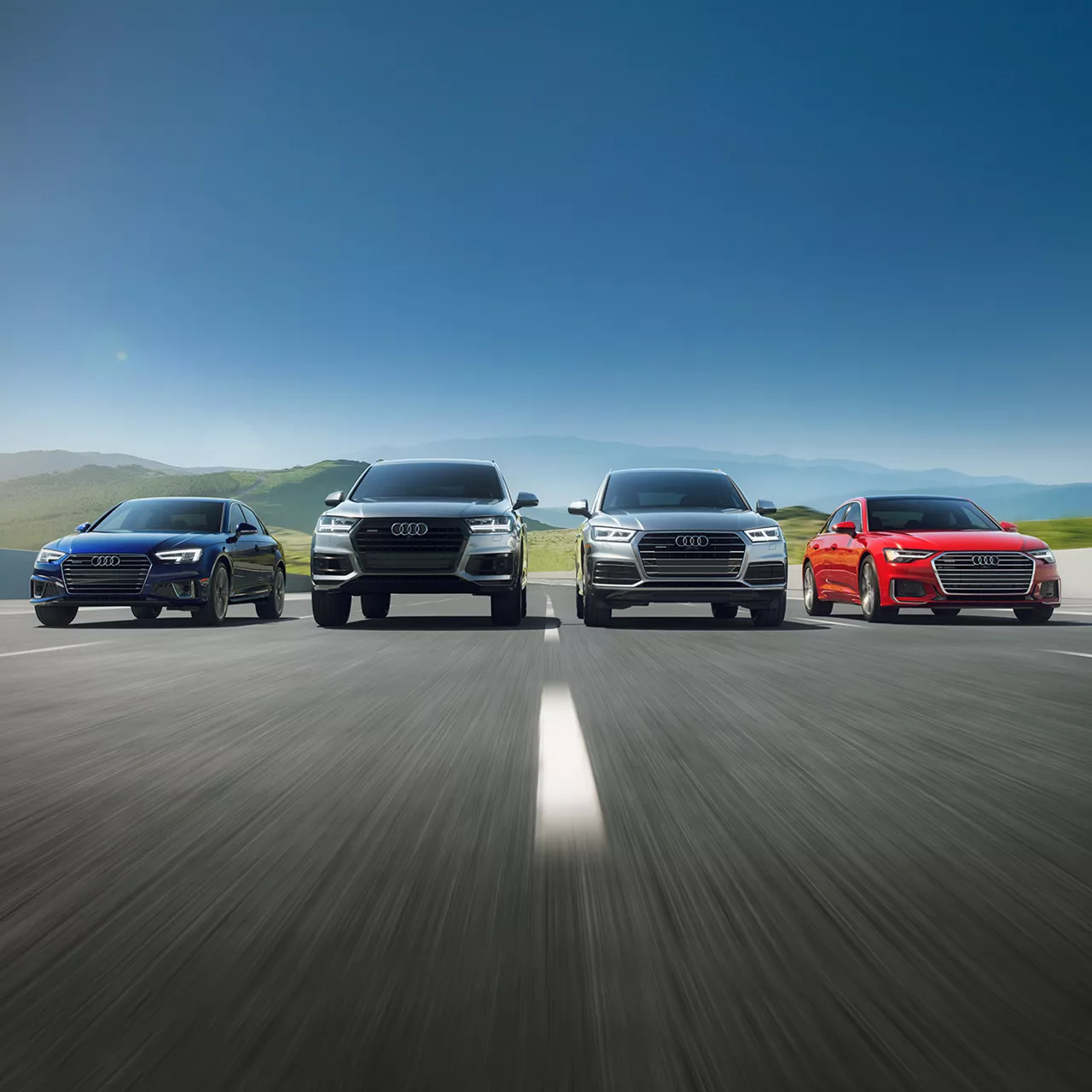 Front view of a range of Audi models in motion. 