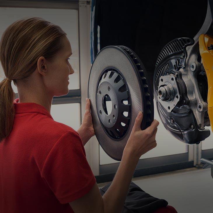 A close-up photo of an Audi Certified Technician in a collision repair shop fixing the wheel of an Audi vehicle.