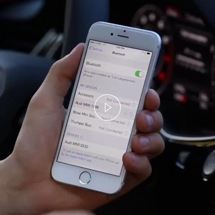 A close-up photo of someone's hand holding an Apple iPhone screen displaying the Bluetooth pairing option.