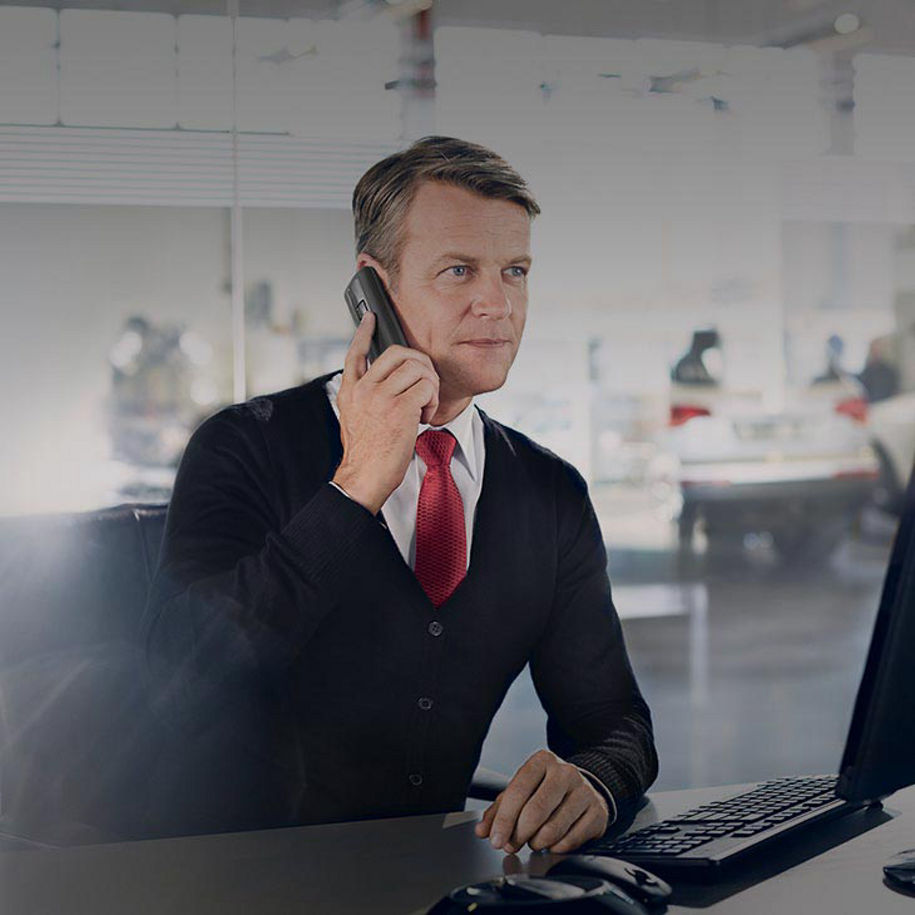 A close-up photo of a man in a suit on the phone calling Audi owner assistance for help.