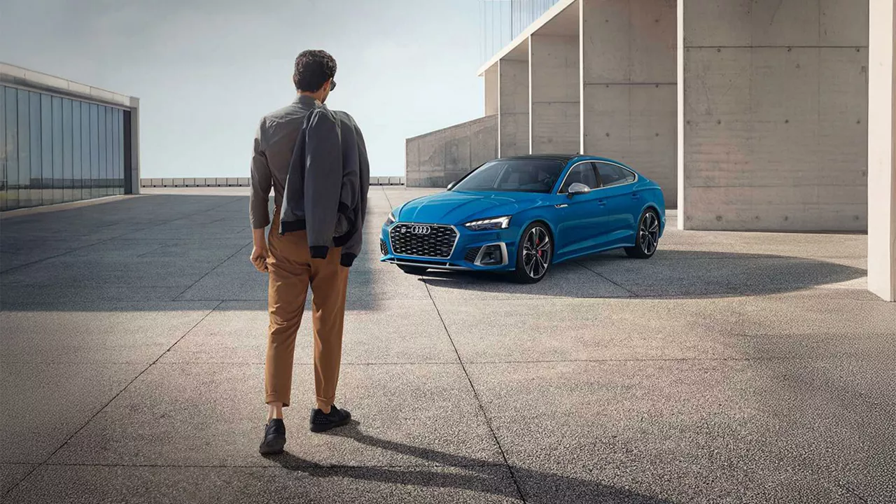 Man standing in front of a blue Audi A3.