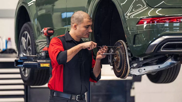Service technician repairing vehicle.