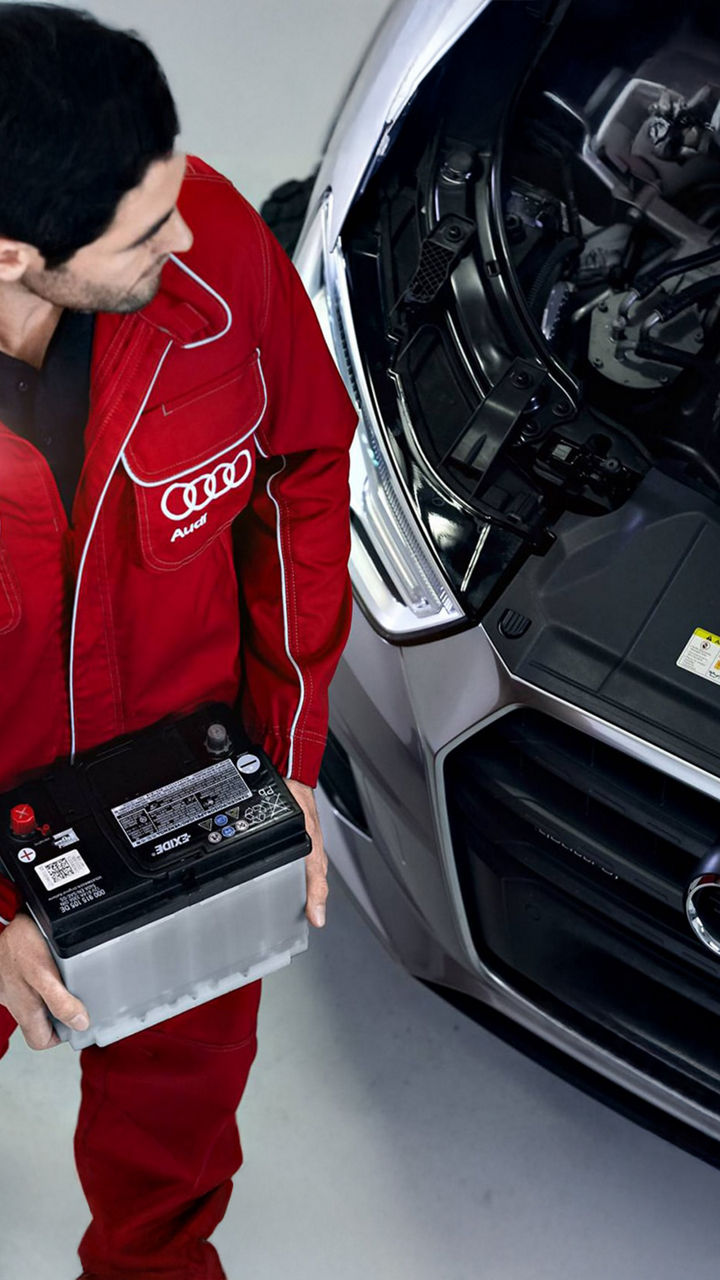 Audi service technician carrying a battery.
