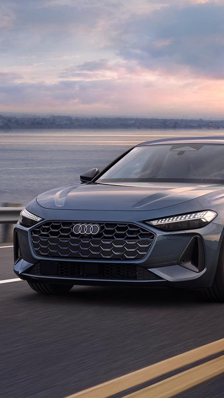 Three-quarter front view of a 2025 Audi A5 model driving on the road.