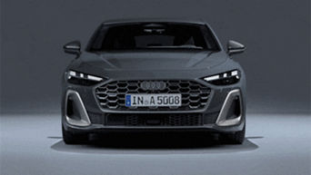 Front view of a 2025 Audi A5 model with headlights on.