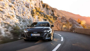 Front view of a 2025 Audi A5 model driving on a mountain road.