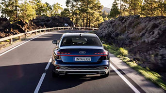 Back view of the 2026 Audi A6 Sedan driving on the road.