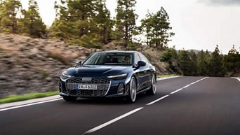 Three-quarter front view of the 2026 Audi A6 Sedan driving on the road.