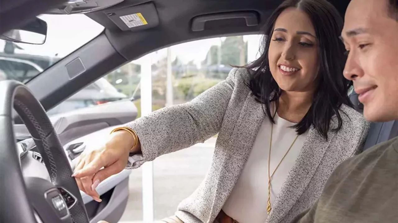 Employé Audi montrant l’intérieur d’un véhicule Audi à un client.