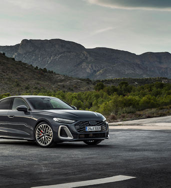 Un Audi A5 stationné en plein air, entouré d’arbres et avec les montagnes en toile de fond.