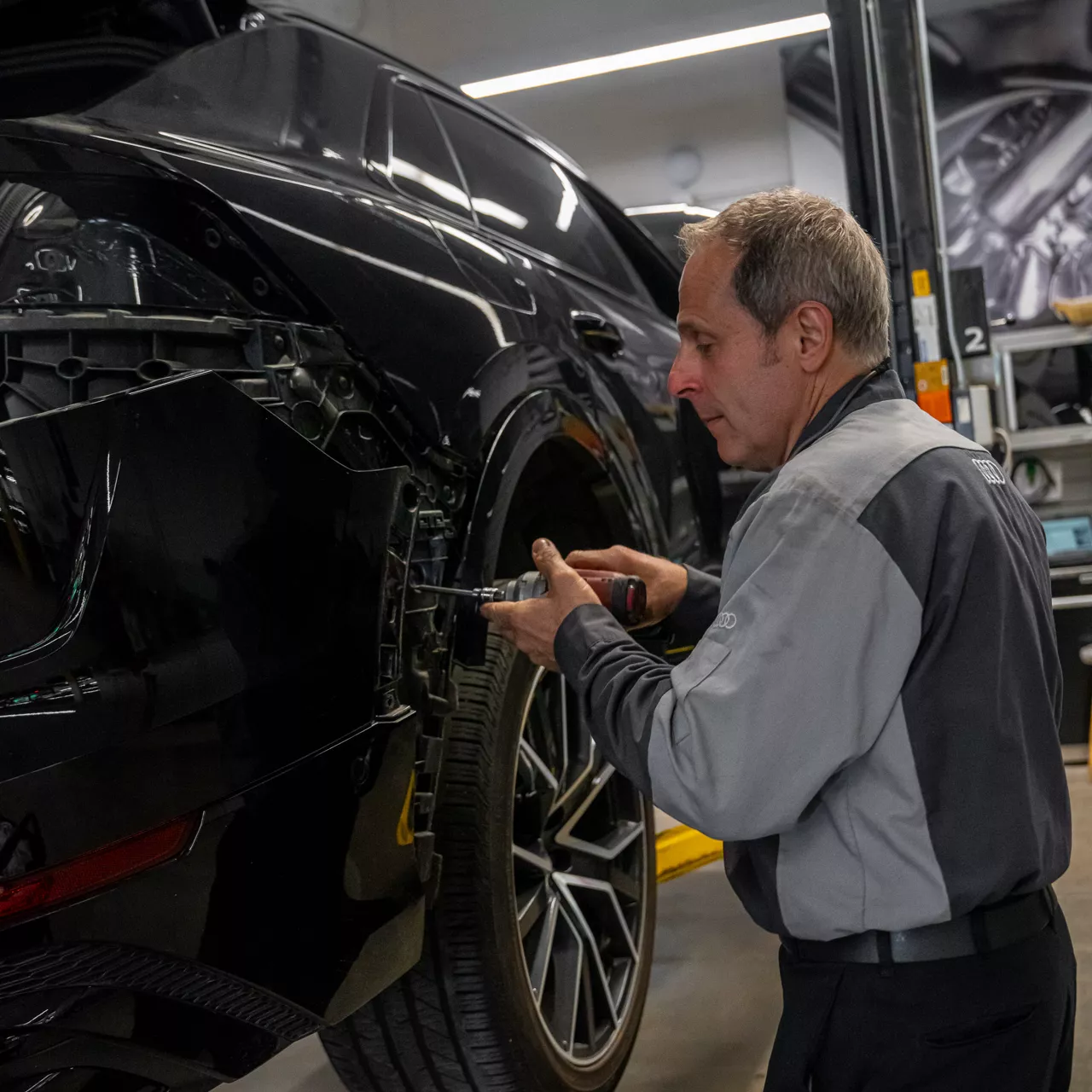 Un technicien du service Audi effectue l’entretien d’un véhicule.