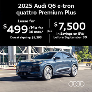 Audi Q6 driving by a building