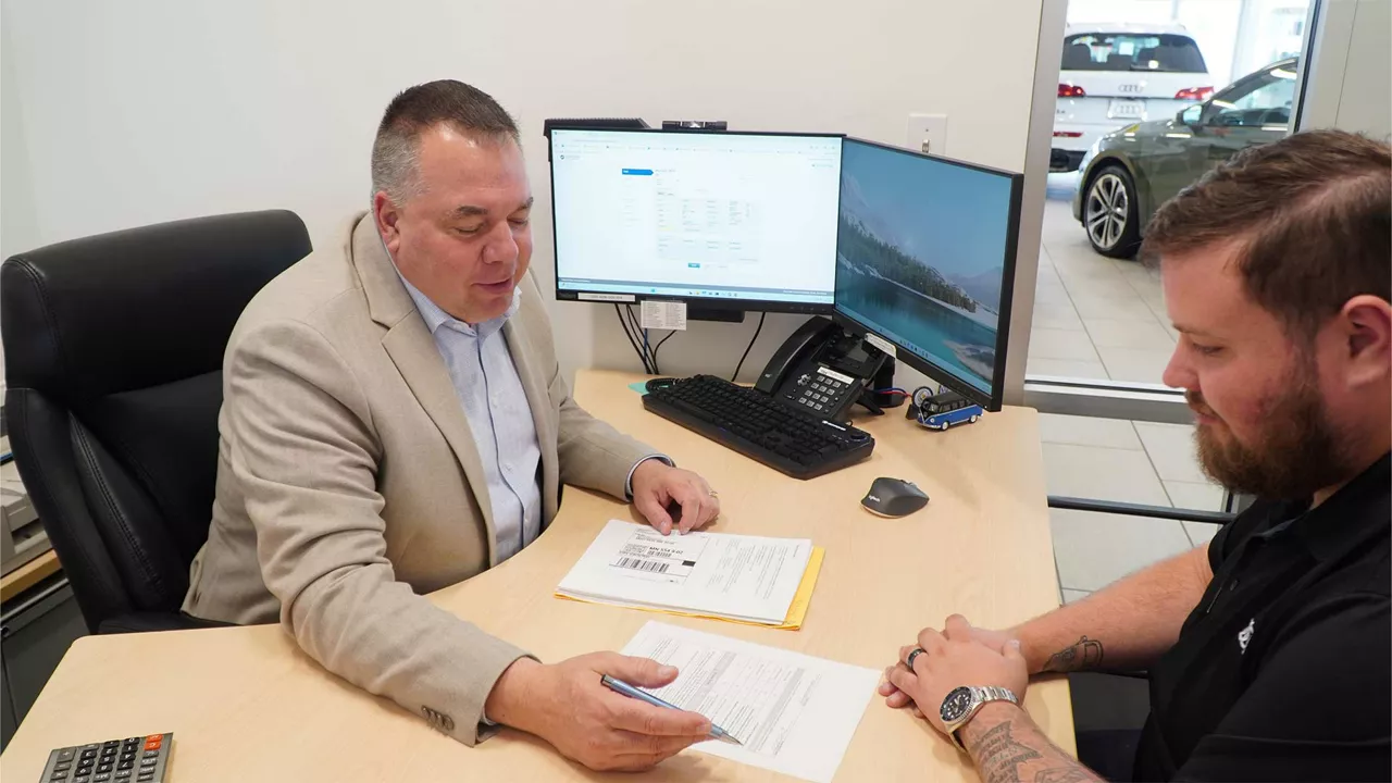 An Audi dealer sitting with a customer in their office