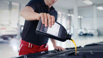 Audi service technician pouring oil.