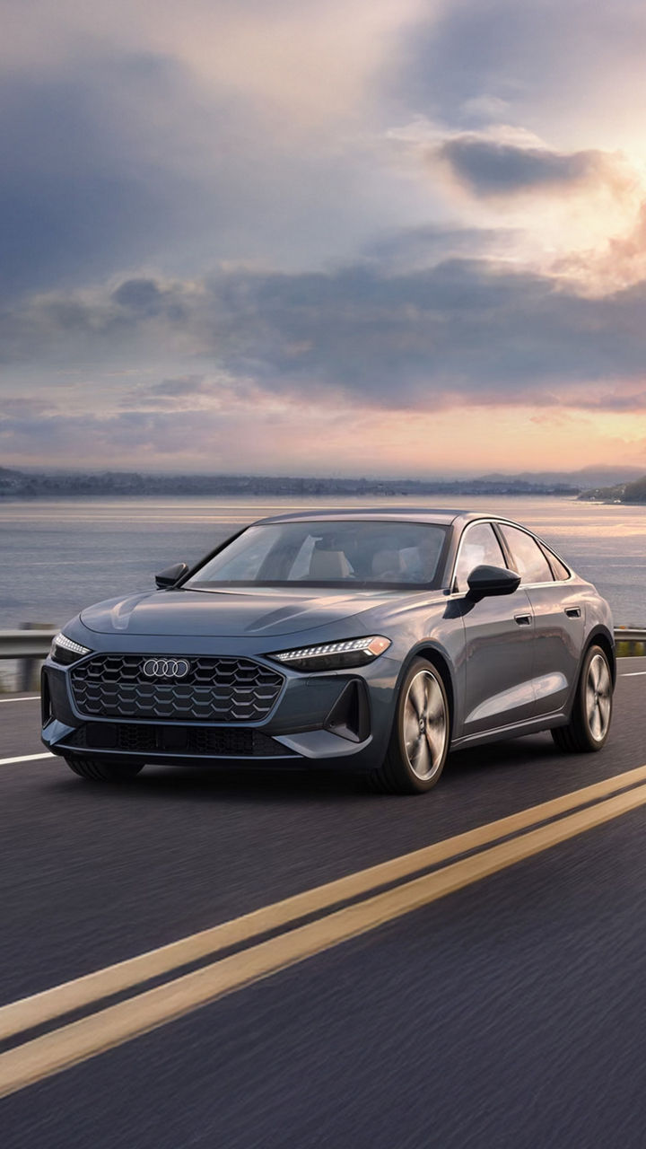 Three-quarter front view of the Audi A5 accelerating on an oceanside road.