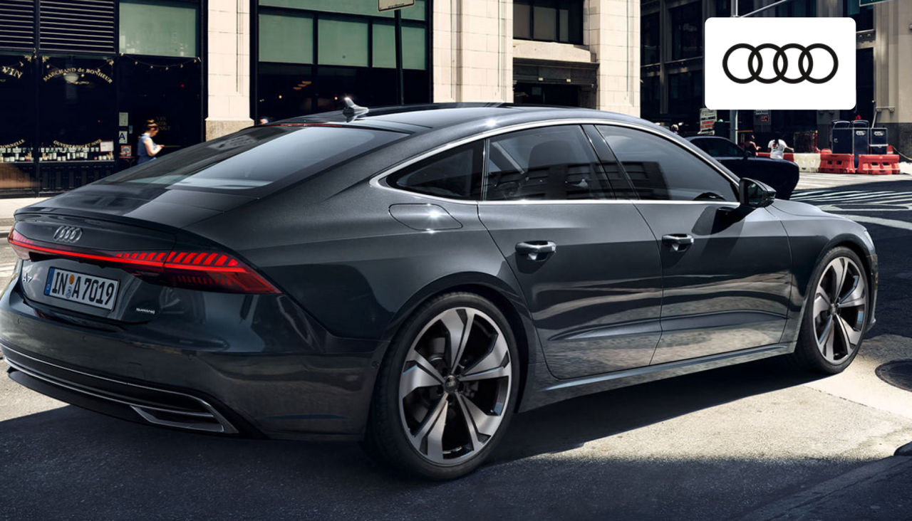 Side view of a 2024 Audi A7 driving along a scenic route near Dayton, showcasing its aerodynamic fastback profile. 