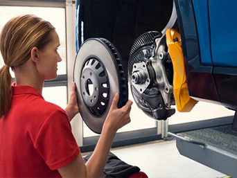 Service technician servicing vehicle with hood open.