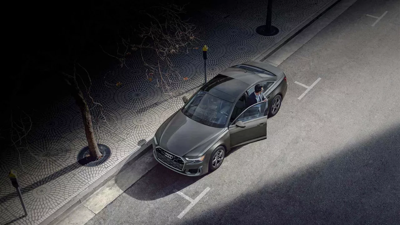 Aerial view of a man getting out of an Audi vehicle parked on the side of the road.