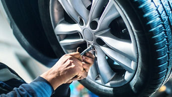 Worker adjusting car wheel.