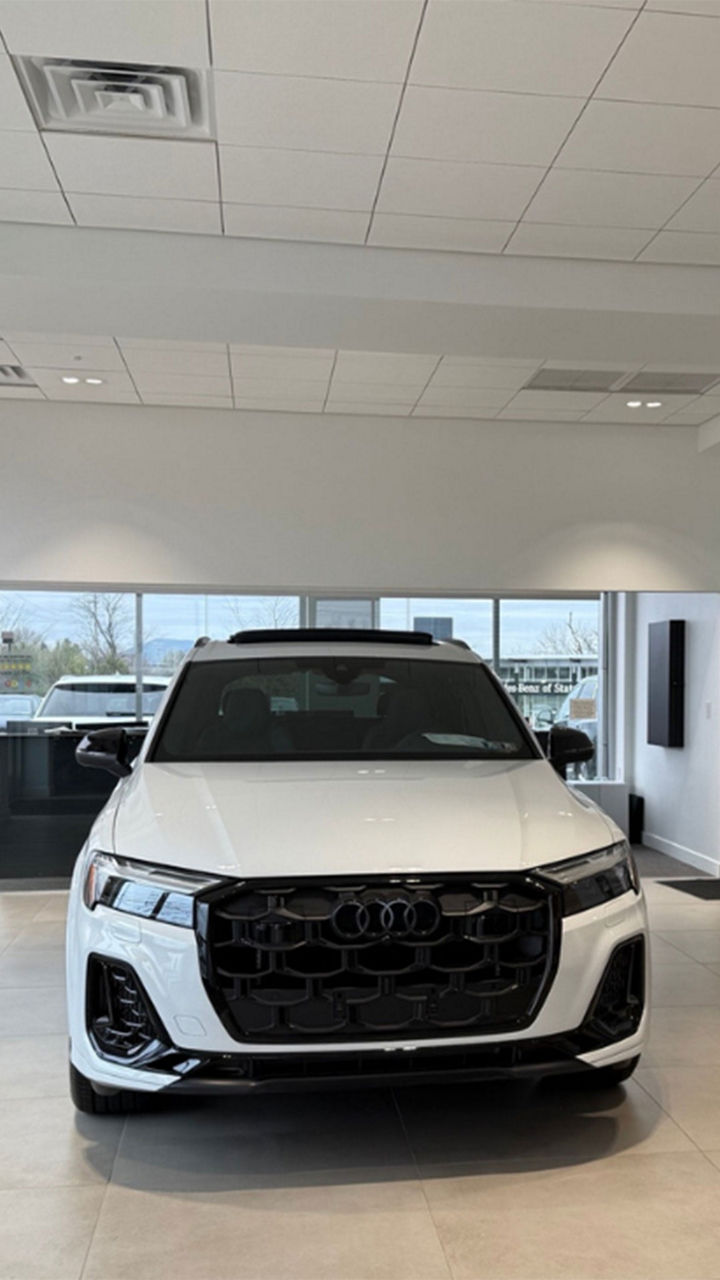 Front view of a white Audi parked in the dealership showroom 